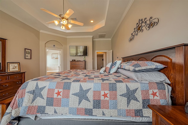 bedroom with crown molding, a raised ceiling, visible vents, ensuite bathroom, and ceiling fan