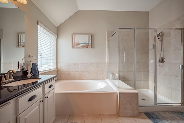 bathroom featuring lofted ceiling, a garden tub, vanity, tile patterned floors, and a stall shower