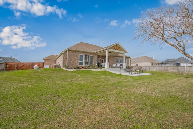 rear view of house featuring a patio, brick siding, a lawn, and a ceiling fan