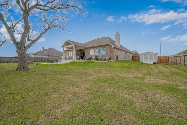 rear view of house featuring a storage shed, a fenced backyard, a chimney, an outdoor structure, and brick siding