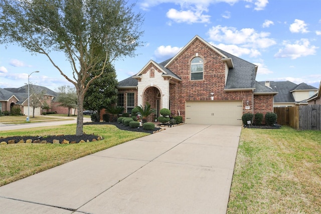 traditional home featuring driveway, fence, roof with shingles, a front yard, and brick siding