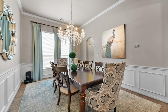 dining room featuring crown molding, wood finished floors, visible vents, and arched walkways