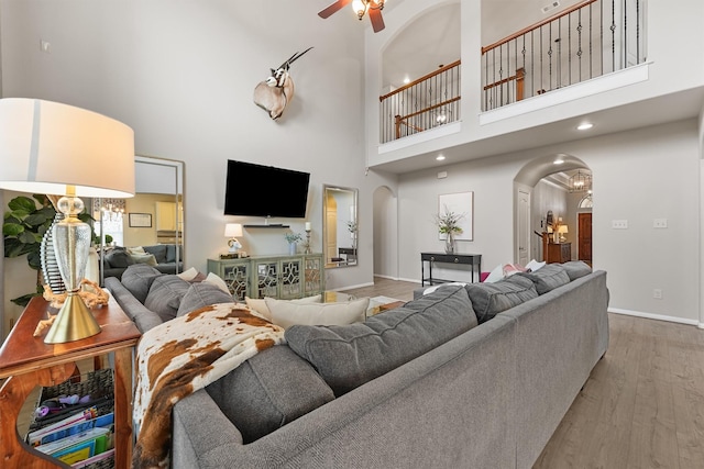 living room with visible vents, wood finished floors, arched walkways, baseboards, and ceiling fan