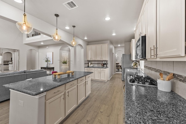 kitchen with visible vents, open floor plan, light wood-style flooring, arched walkways, and stainless steel appliances