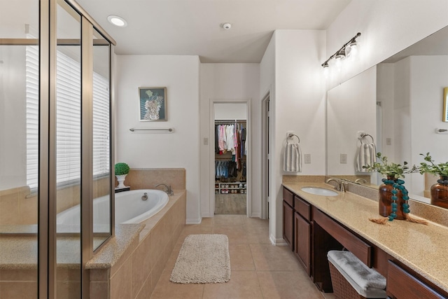 bathroom with tile patterned floors, a walk in closet, recessed lighting, a bath, and vanity