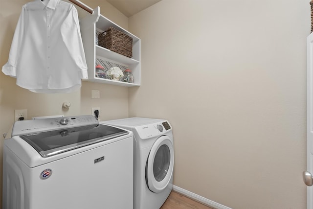 laundry area with light wood finished floors, laundry area, independent washer and dryer, and baseboards