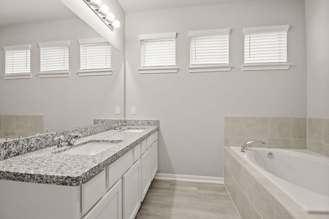 full bathroom with baseboards, double vanity, a sink, and plenty of natural light