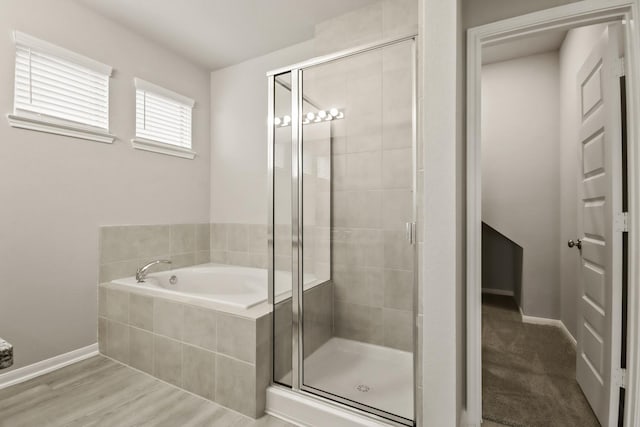 bathroom featuring baseboards, a stall shower, wood finished floors, and a garden tub