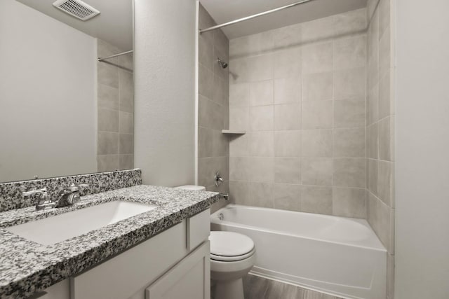 full bath with vanity, visible vents, toilet, wood finished floors, and washtub / shower combination