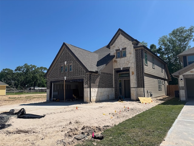 view of front facade with a garage, brick siding, stone siding, and fence