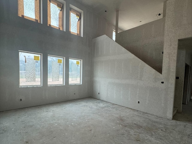 unfurnished room featuring concrete floors and a towering ceiling