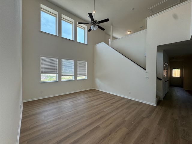 18757 Lucas Michael Way, New Caney, TX 77357 - unfurnished living room with ceiling fan, healthy amount of natural light, wood finished floors, stairs, and a high ceiling
