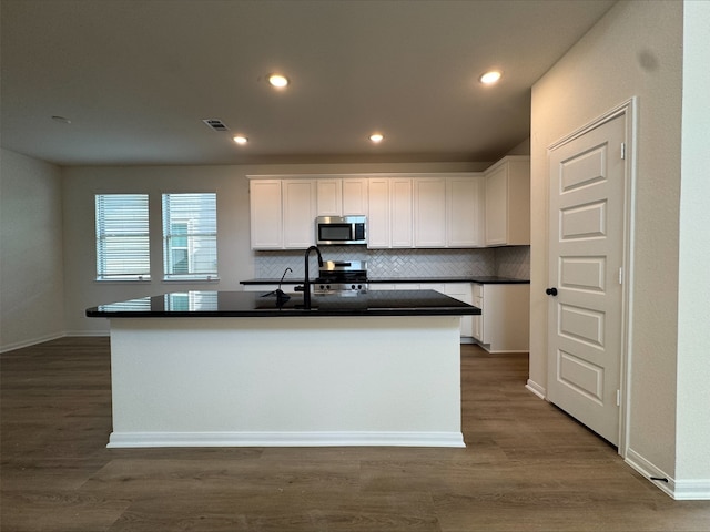 18757 Lucas Michael Way, New Caney, TX 77357 - kitchen featuring appliances with stainless steel finishes, a sink, dark countertops, white cabinetry, and tasteful backsplash