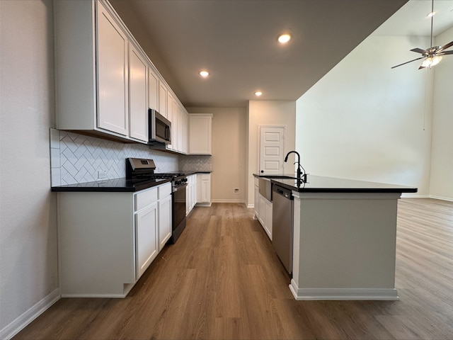 18757 Lucas Michael Way, New Caney, TX 77357 - kitchen with appliances with stainless steel finishes, dark countertops, a sink, wood finished floors, and backsplash