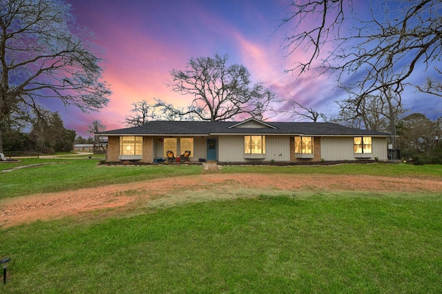 view of front facade featuring a lawn and dirt driveway