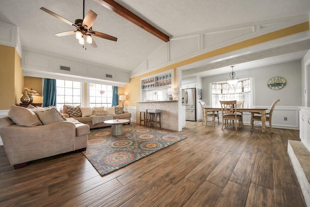 living area with dark wood-type flooring, beamed ceiling, a ceiling fan, and a wealth of natural light