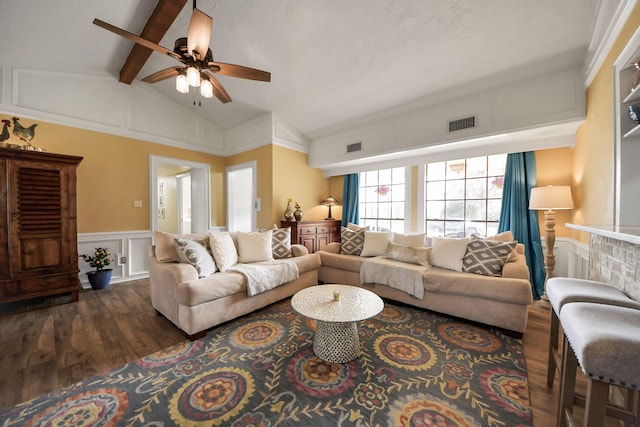 living area with visible vents, lofted ceiling with beams, wainscoting, wood finished floors, and a decorative wall