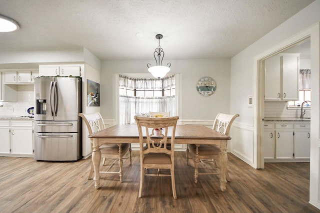 dining space with a wainscoted wall, plenty of natural light, and light wood-style flooring