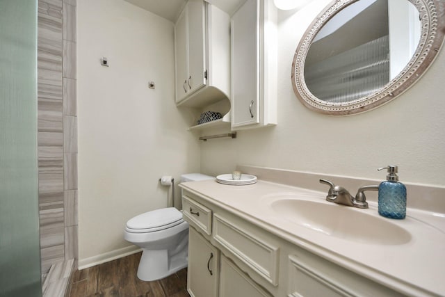 bathroom featuring toilet, wood finished floors, a shower, baseboards, and vanity