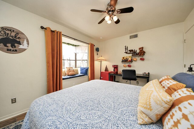 bedroom featuring ceiling fan, visible vents, baseboards, and wood finished floors