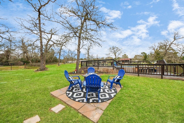 view of yard featuring a patio, an outdoor fire pit, a deck, and fence