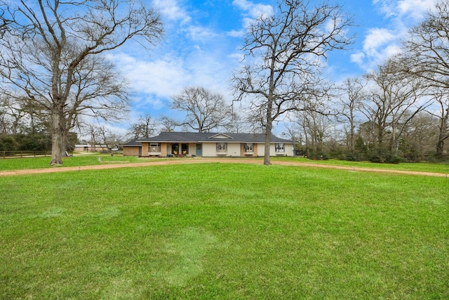 ranch-style home with a front lawn, an attached garage, and dirt driveway