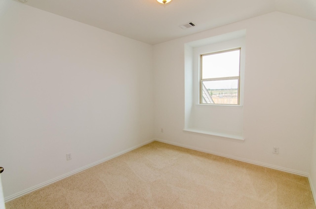 unfurnished room featuring vaulted ceiling, baseboards, light colored carpet, and visible vents