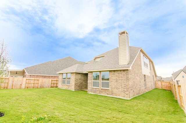 18122 Glenlyon Dr, Richmond, TX 77407 - back of property featuring a fenced backyard, a chimney, brick siding, and a yard