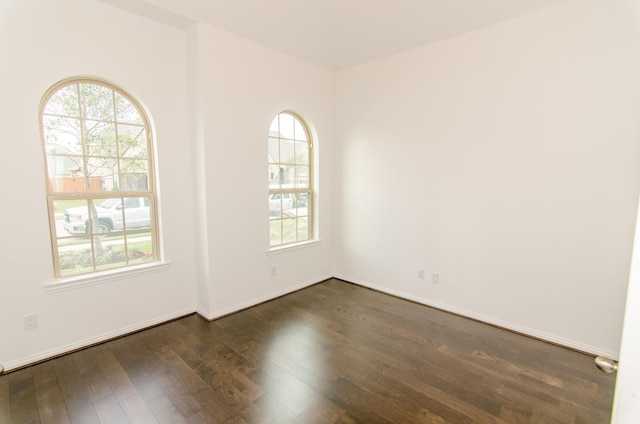 unfurnished room featuring baseboards and dark wood-style flooring