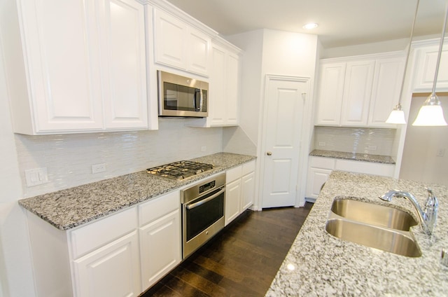 kitchen featuring decorative backsplash, dark wood-style flooring, white cabinets, stainless steel appliances, and a sink