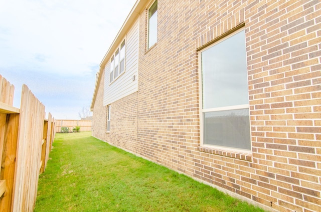 view of side of property featuring a fenced backyard, brick siding, and a lawn