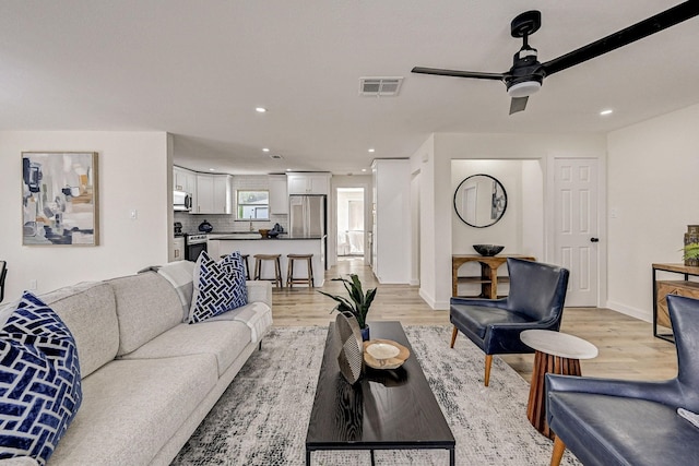 living area featuring recessed lighting, visible vents, light wood-style floors, ceiling fan, and baseboards