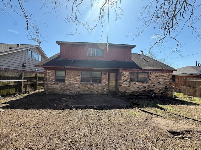 rear view of house with a patio, brick siding, and a fenced backyard