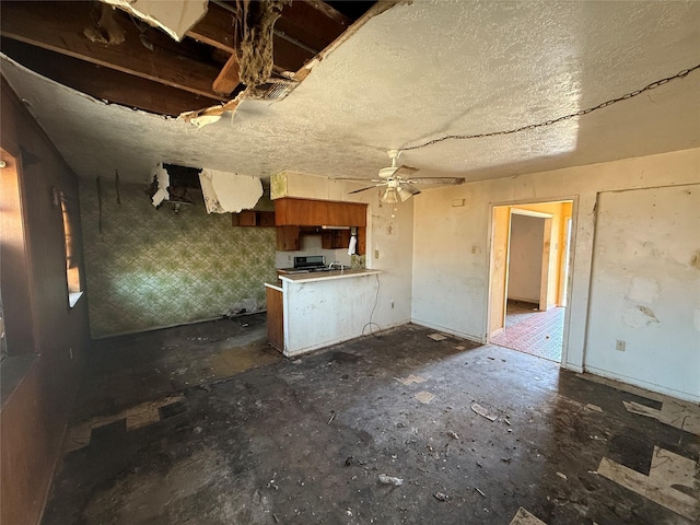 kitchen featuring a ceiling fan, brown cabinets, a peninsula, light countertops, and a textured ceiling