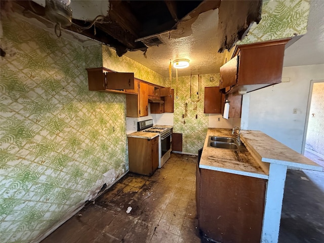 kitchen featuring a textured ceiling, under cabinet range hood, a sink, light countertops, and white gas range