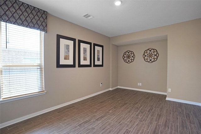 spare room with a wealth of natural light, wood finished floors, visible vents, and baseboards