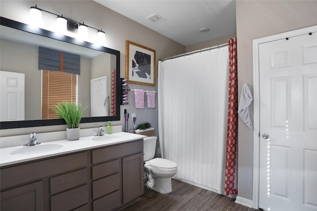 bathroom featuring visible vents, a sink, toilet, and double vanity