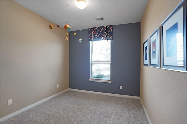 carpeted spare room featuring baseboards and visible vents