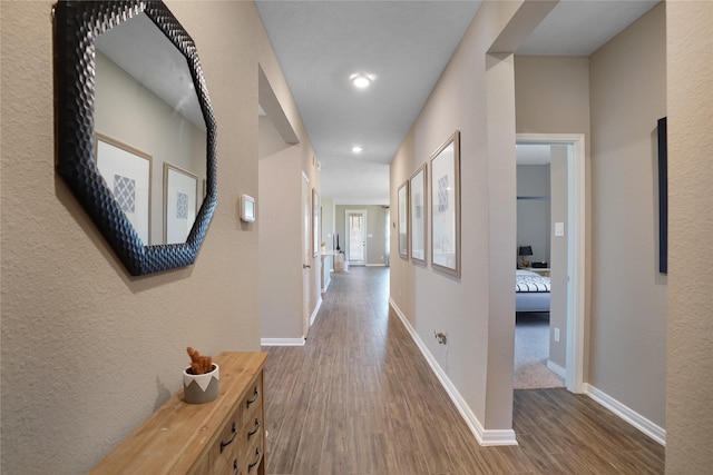 corridor featuring baseboards and wood finished floors