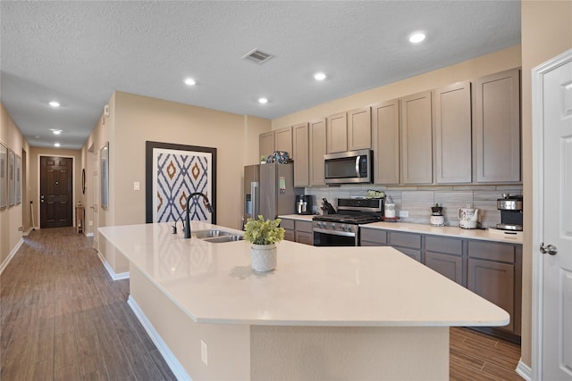 kitchen with visible vents, an island with sink, dark wood-style floors, appliances with stainless steel finishes, and a sink