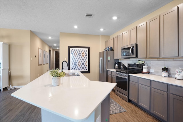 kitchen featuring dark wood-style floors, stainless steel appliances, light countertops, visible vents, and a sink