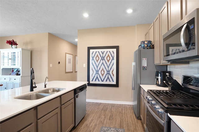 kitchen featuring light wood-style flooring, stainless steel appliances, a sink, light countertops, and tasteful backsplash