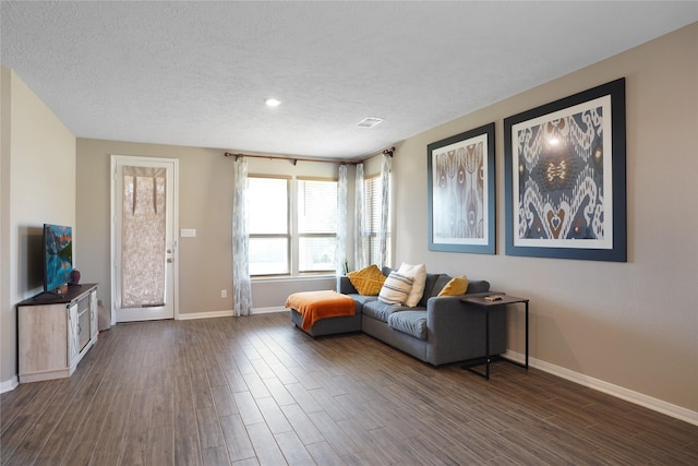 living area with dark wood-style floors, a textured ceiling, and baseboards