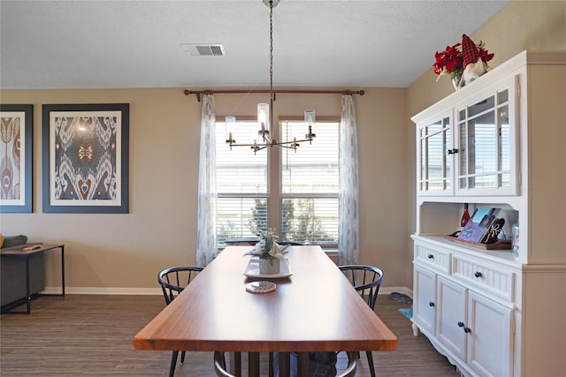 dining room with a textured ceiling, dark wood-type flooring, visible vents, and an inviting chandelier