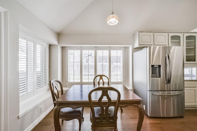 dining space featuring lofted ceiling, wood finished floors, and baseboards