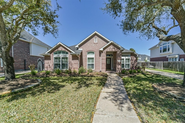 view of front of property featuring brick siding, a front yard, and fence