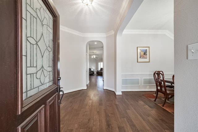 entrance foyer featuring ceiling fan, arched walkways, dark wood-style floors, and crown molding