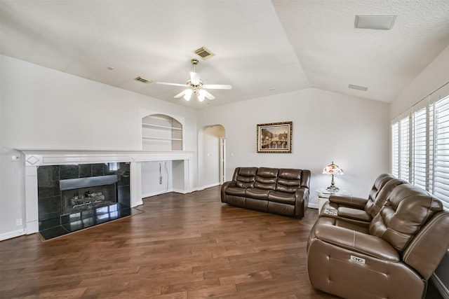 living area featuring vaulted ceiling, visible vents, wood finished floors, and built in features