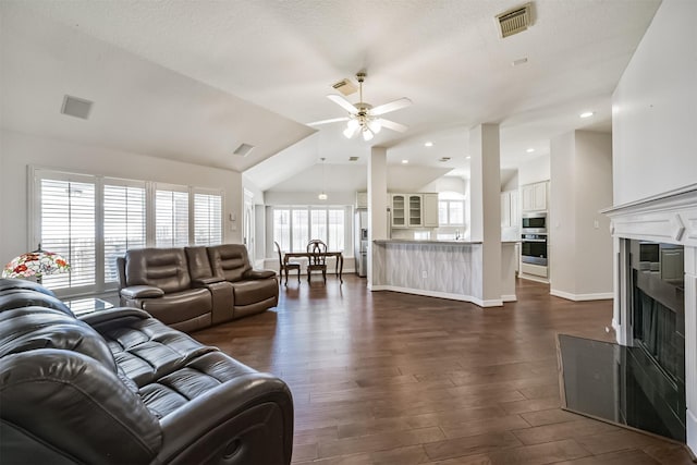 living room with visible vents, dark wood-type flooring, a ceiling fan, and vaulted ceiling