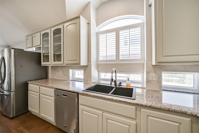 kitchen with a sink, backsplash, dark wood finished floors, stainless steel appliances, and glass insert cabinets